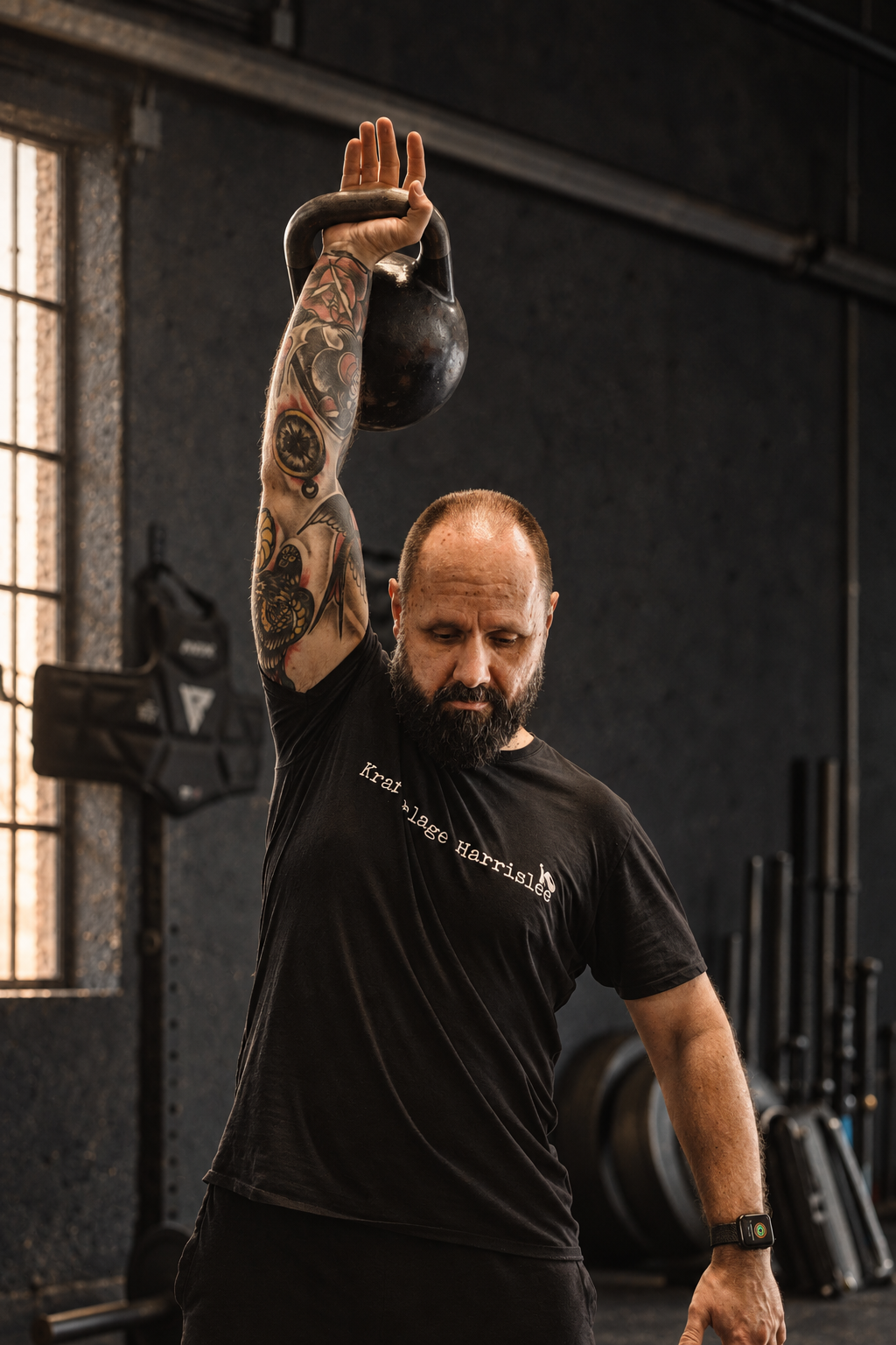 Jörg Siegwarth hält eine Kettlebell mit gestrecktem Arm über dem Kopf